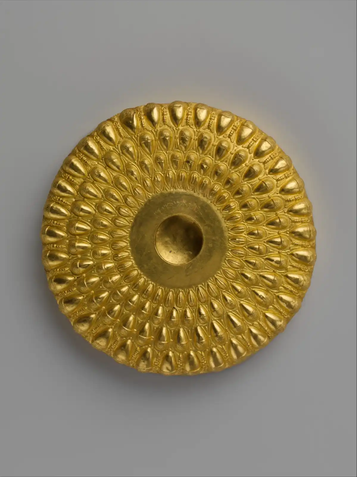 Gold libation bowl worked in relief with concentric rings of bees among acorns and beechnuts.