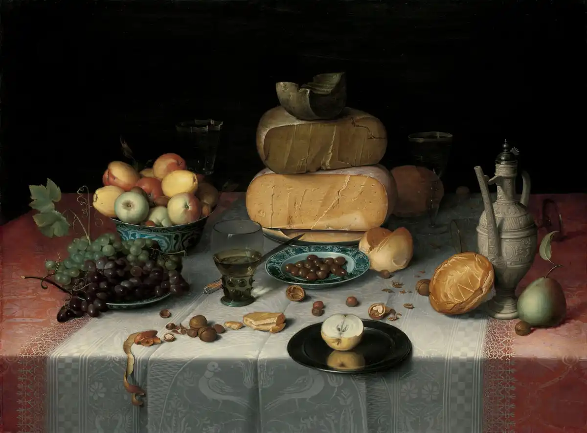 A stacked tower of cheese wheels on pewter with grapes, apples, olives and bread on a damask cloth.